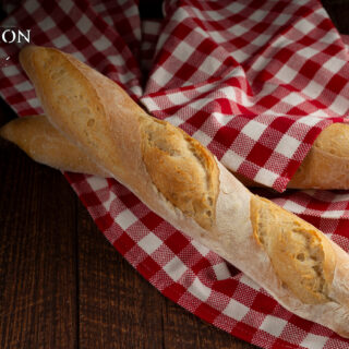 Photo of two baguettes sitting on a red gingham towel. The Clair Obscur: Expedition 33 logos is in the top left.